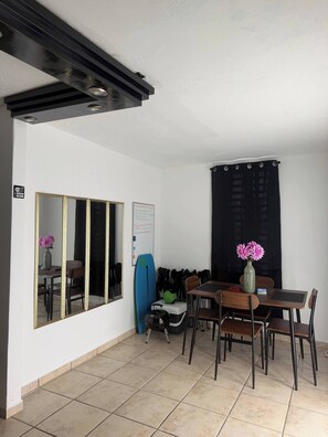A room with a dining table, chairs, a mirror, a surfboard, and a whiteboard. - Your Adventure Home El Yunque, Culebra & Icacos (Luquillo city)