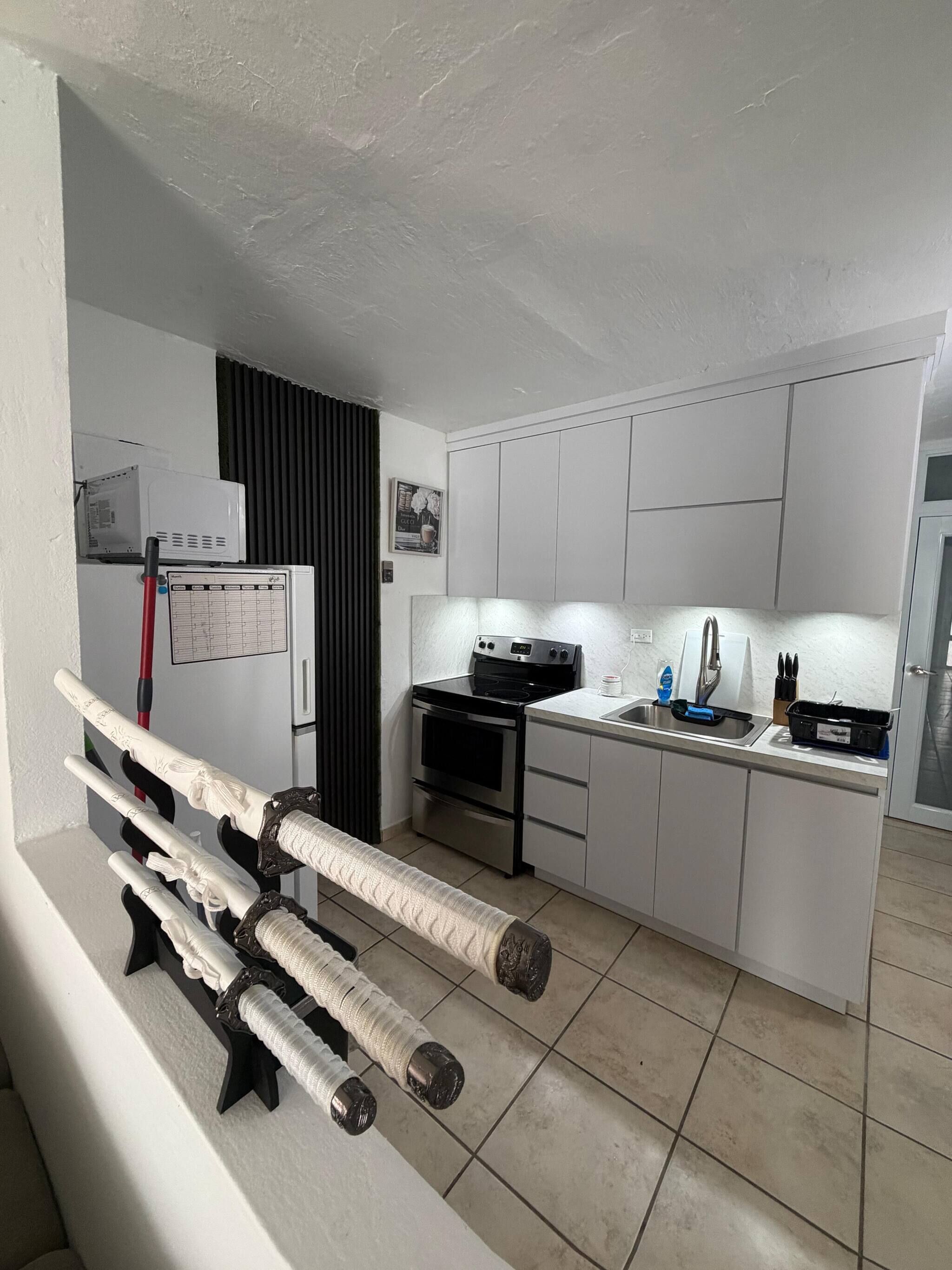 A compact kitchen with white cabinets, a black stove, and a small countertop.