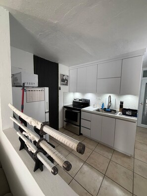 A compact kitchen with white cabinets, a black stove, and a small countertop. - Your Adventure Home El Yunque, Culebra & Icacos (Luquillo city)