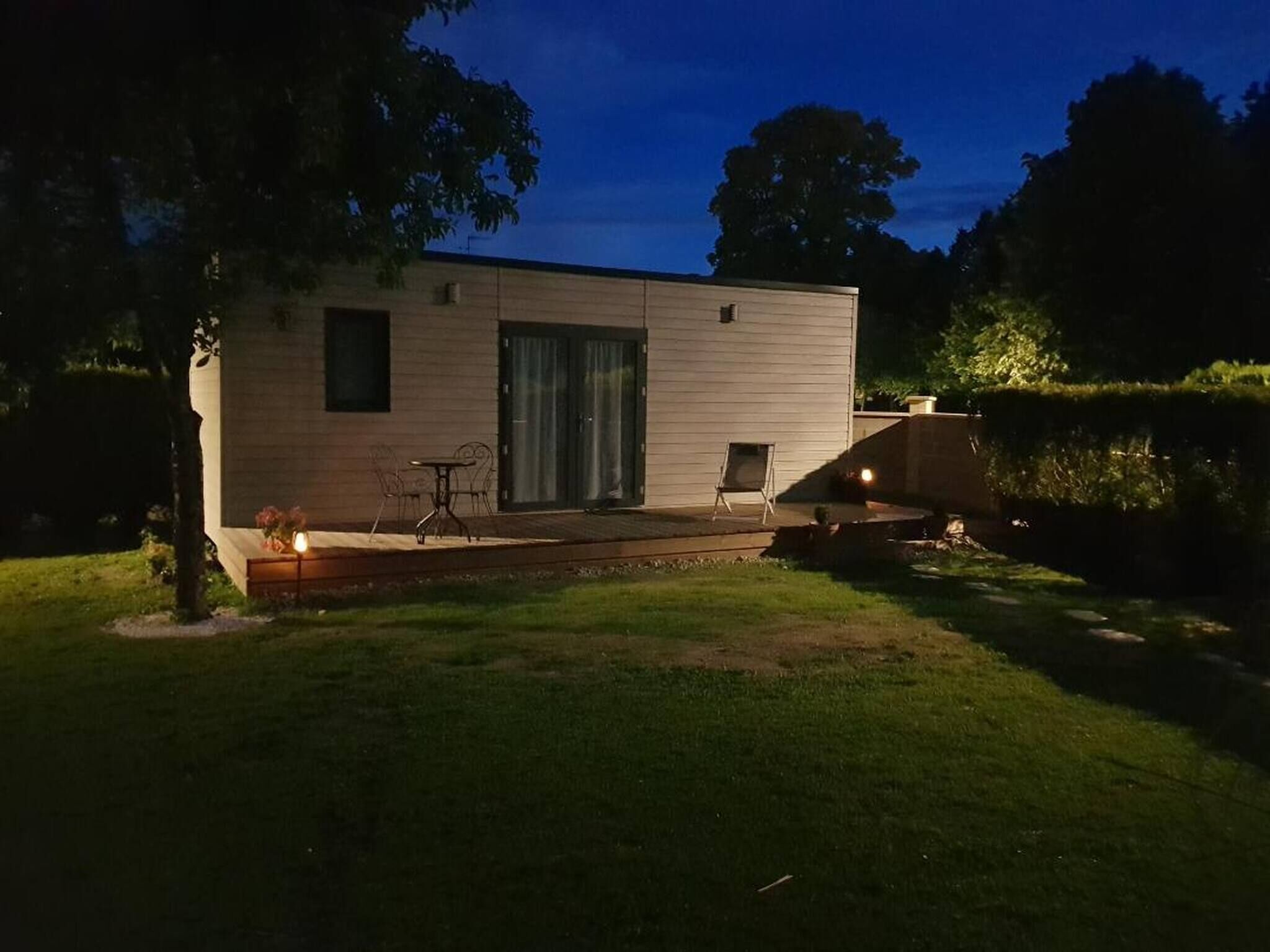 Une maison moderne de plain-pied dotée d’un patio, d’une table et de chaises.