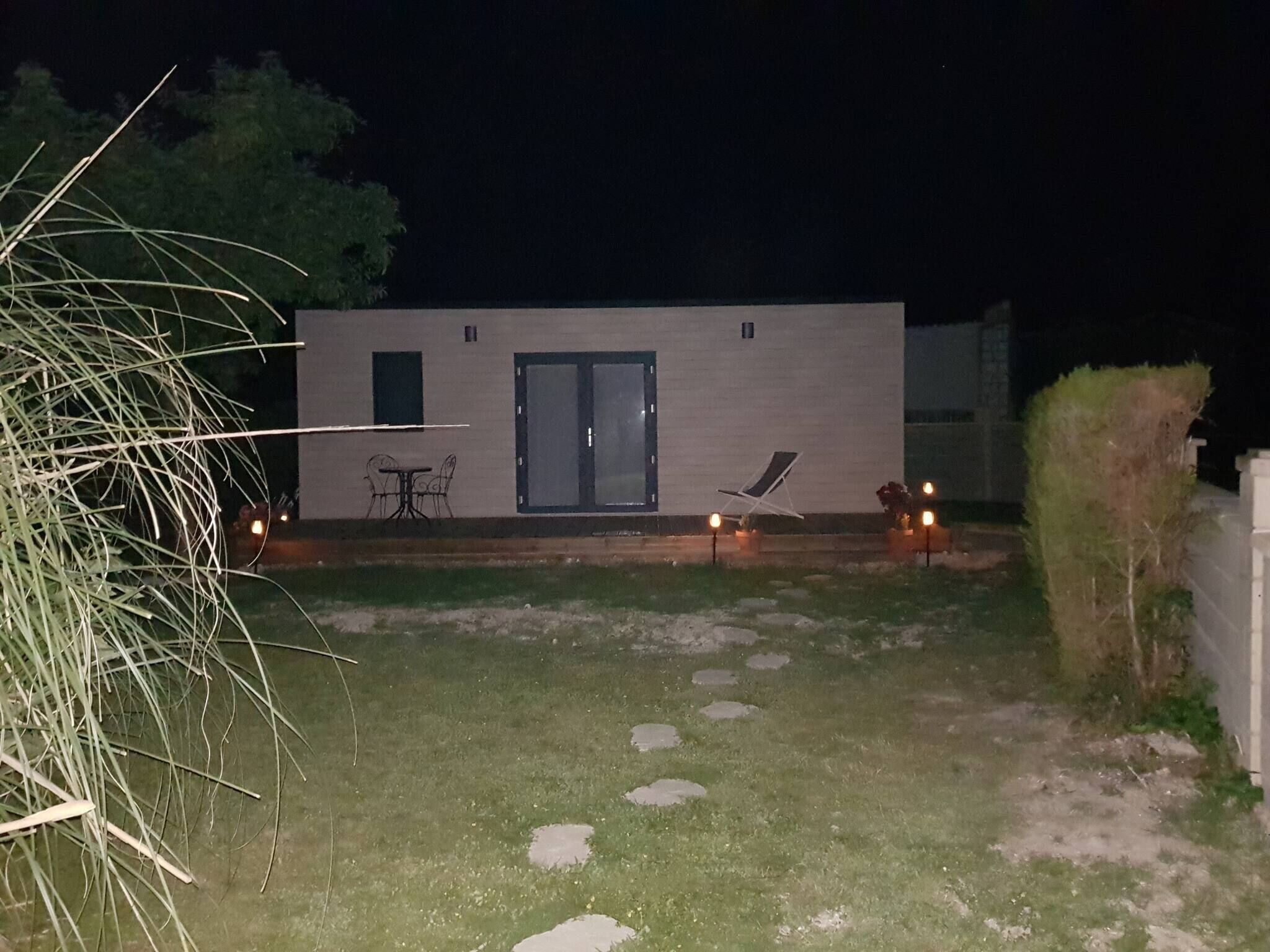 Ein modernes Gebäude mit Flachdach, einer Tür und einer kleinen Terrasse mit Tisch und Stühlen.