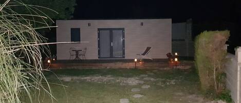A modern building with a flat roof, a door, and a small patio area with a table and chairs.