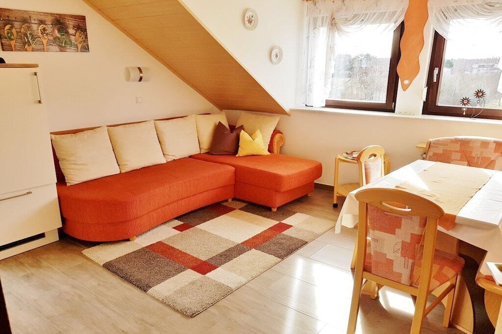 A cozy room with a sectional sofa, a dining table, and a window with curtains.