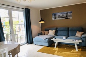 A living room with a sofa, a coffee table, a lamp, and a painting on the wall. - Holiday apartment with 1 bedroom (Ostseebad Prerow)