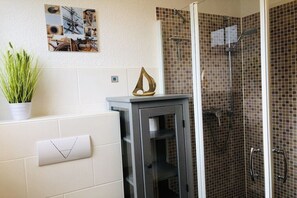 A bathroom with a shower, a potted plant, and a wall-mounted towel rack. - Holiday apartment with 1 bedroom (Ostseebad Prerow)