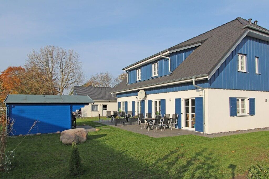 A two-story building with a blue exterior, a covered patio area with outdoor seating, and a small shed.