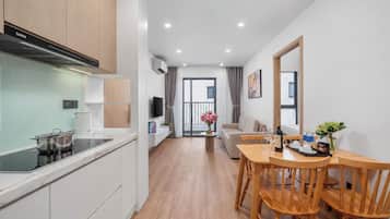 Una cocina moderna con estufa integrada, un comedor con sillas de madera y vistas al exterior.