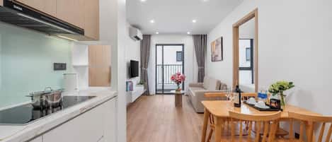 Una cocina moderna con estufa integrada, un comedor con sillas de madera y vistas al exterior.