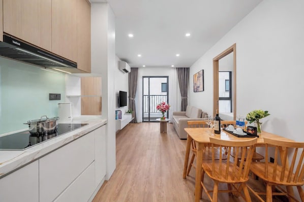 Una cocina moderna con estufa integrada, un comedor con sillas de madera y vistas al exterior.