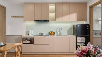 Una cocina moderna con armarios de madera, microondas integrado, hervidor y refrigerador.