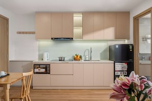 Una cocina moderna con armarios de madera, microondas integrado, hervidor y refrigerador.