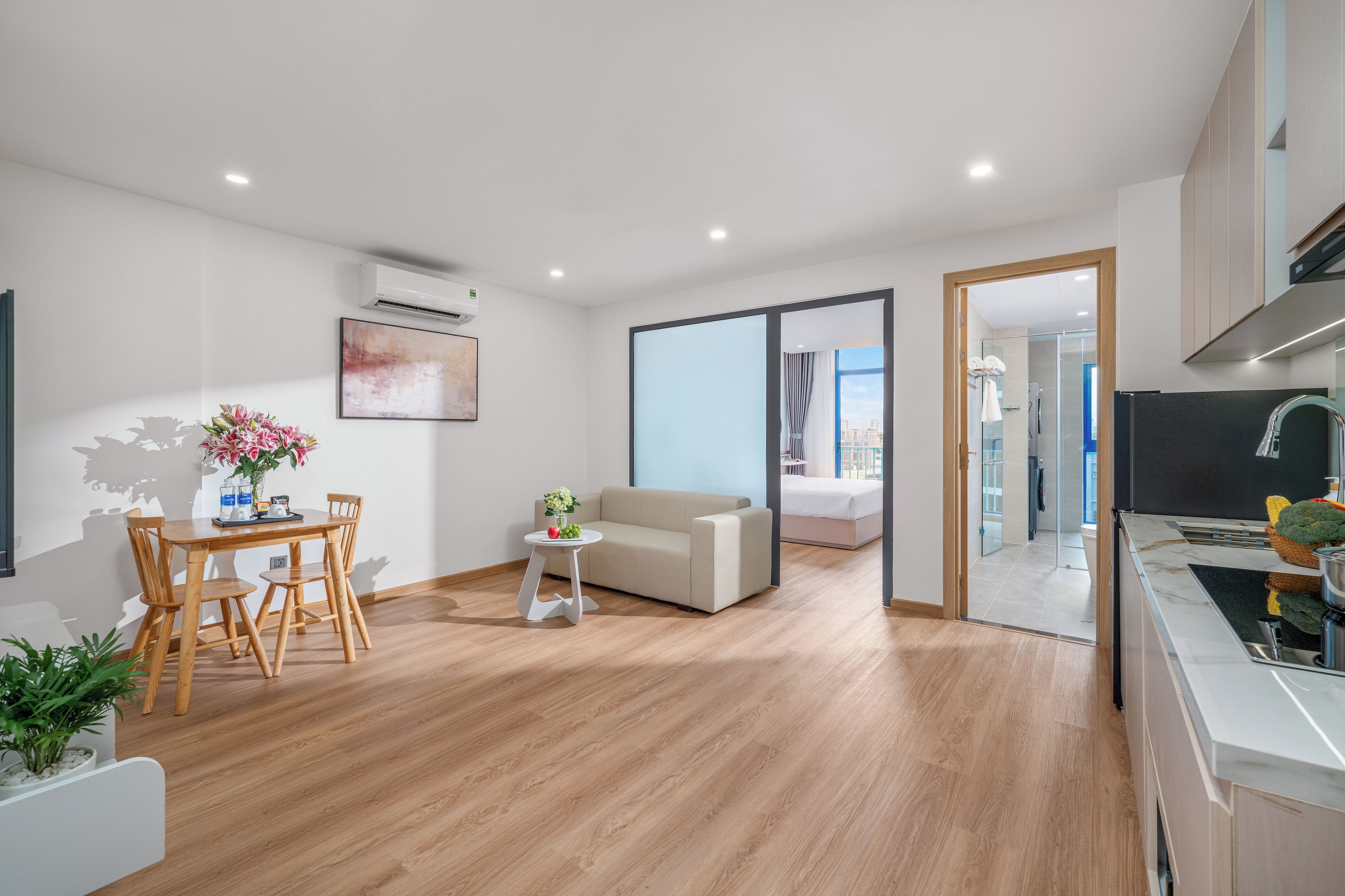 Una sala de estar moderna con comedor, un sofá, una cama y una cocina con vistas.