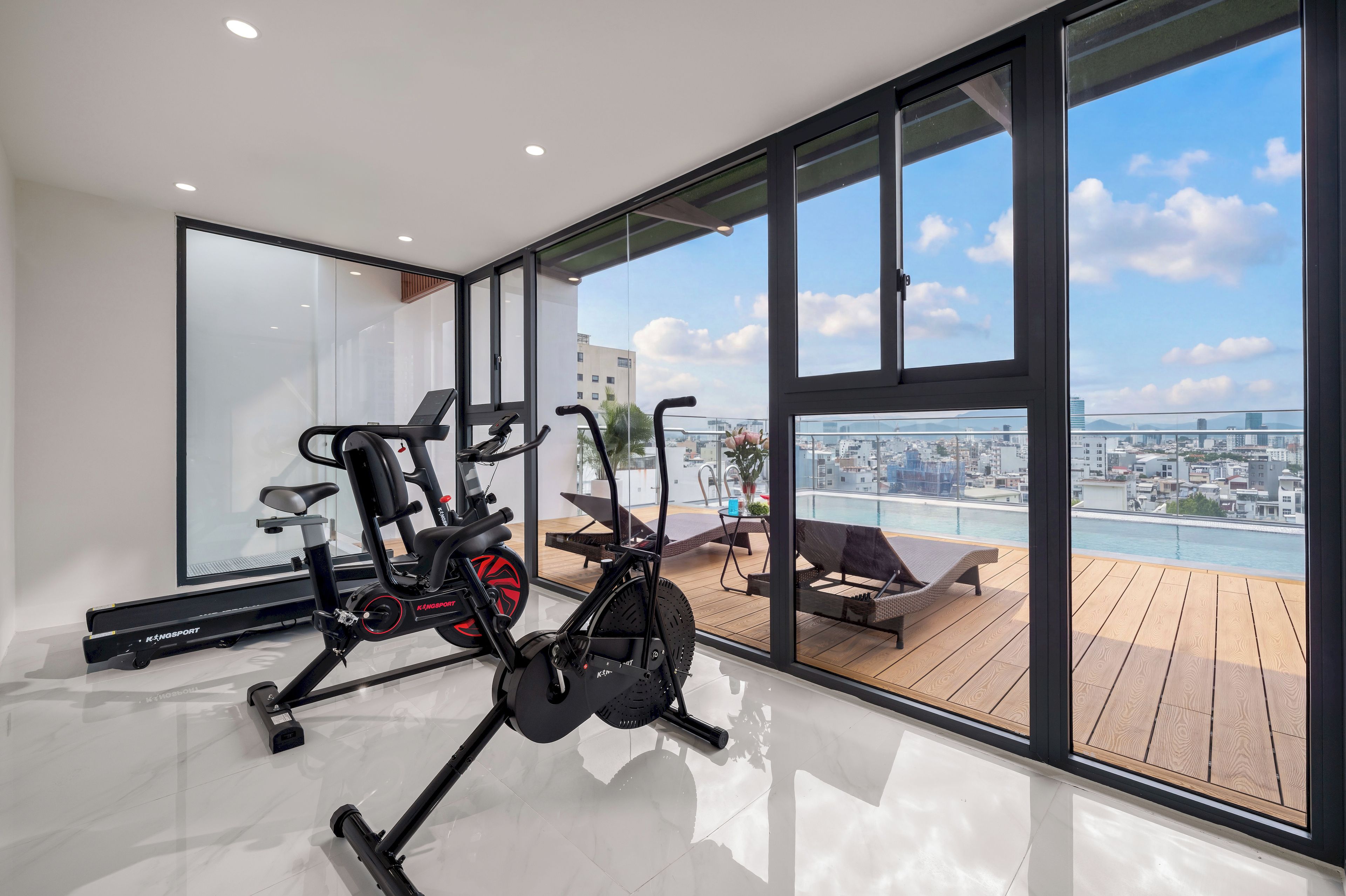 A modern gym with exercise equipment and a city view through large windows.