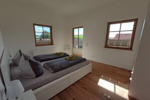 A bedroom with a bed, two windows, and a radiator. - Holiday apartment in Görisried with Wi-Fi (Görisried)