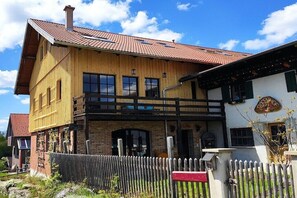 A two-story wooden building with a balcony, a brick section, and a red-tiled roof. - Holiday apartment in Görisried with Wi-Fi (Görisried)