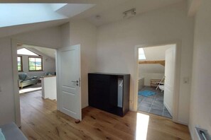 A room with a wooden floor, a black cabinet, and a door leading to another room. - Holiday apartment in Görisried with Wi-Fi (Görisried)