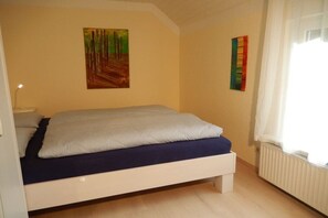 Une chambre à coucher avec un lit, un tableau accroché au mur et une fenêtre avec des rideaux.