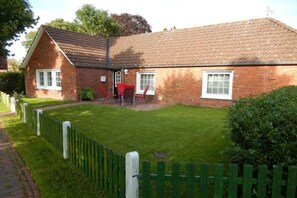 Une maison en briques avec un toit en tuiles, une allée pavée et une pelouse verdoyante.