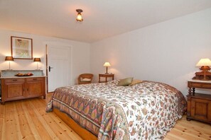 Ein Schlafzimmer mit einem Bett, einer Kommode, zwei Lampen und einer Tür.
