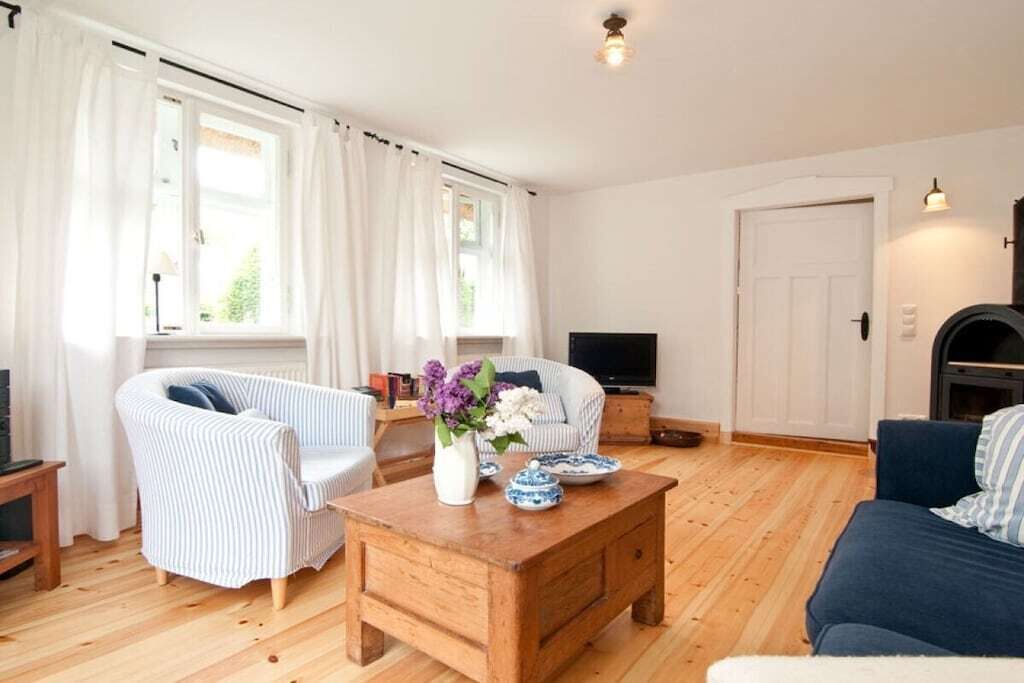 A living room with a wooden coffee table, two striped armchairs, a sofa, a television, and a fireplace.