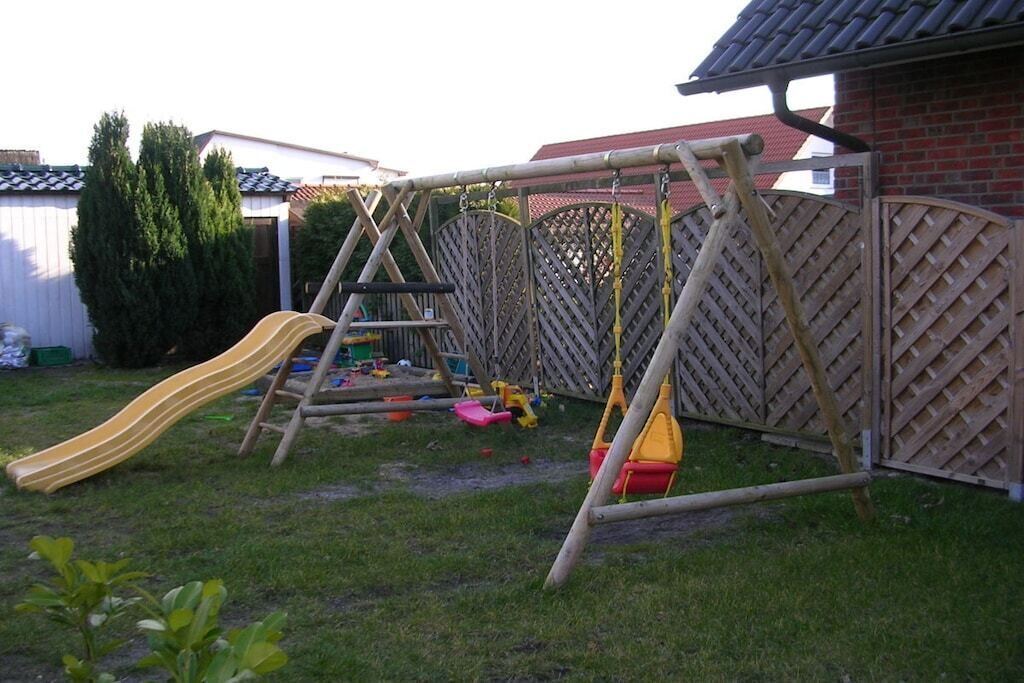 A wooden swing set with a slide in a backyard.
