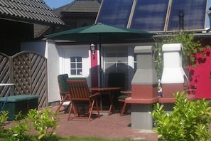 An outdoor patio with a table and chairs, a green umbrella, and a brick wall. - 3-room apartment near the harbor - ground floor with terrace (Zingst)