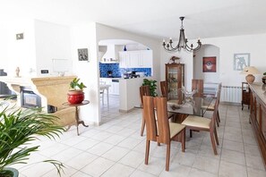 A spacious living area with a dining table and chairs, a kitchen in the background, and a chandelier. - Holiday home with 2 bedrooms (Tavernes, Frankreich)