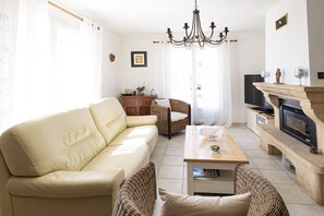 A living room with a sofa, wicker chairs, a coffee table, a fireplace, and a television. - Holiday home with 2 bedrooms (Tavernes, Frankreich)