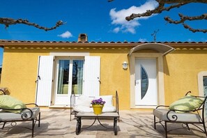 A yellow building with a tiled roof, a door, and two outdoor seating areas with metal chairs and cushions. - Holiday home with 2 bedrooms (Tavernes, Frankreich)
