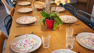 A dining table set with plates, glasses, and cutlery, with a potted plant and a mirror on the wall.