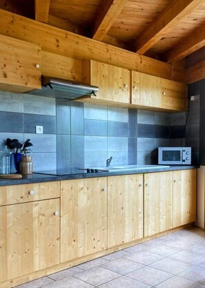 A kitchen with wooden cabinets, a microwave, and a tiled backsplash. - The Balcons du Haut-Doubs in the Heart of the Natural Park (Vaucluse)