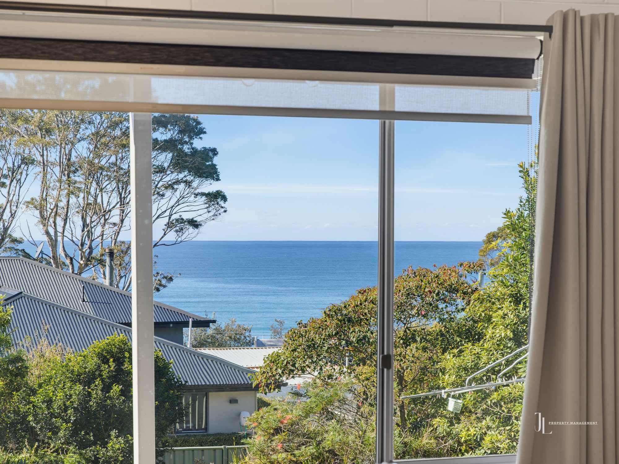 A view through a window with a clear sky and a body of water in the distance.