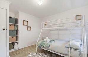A bunk bed with a white metal frame, a wooden ladder, and a small shelf above it. - Coastal Haven | Ocean Views + Pets Welcome. (Denhams Beach)