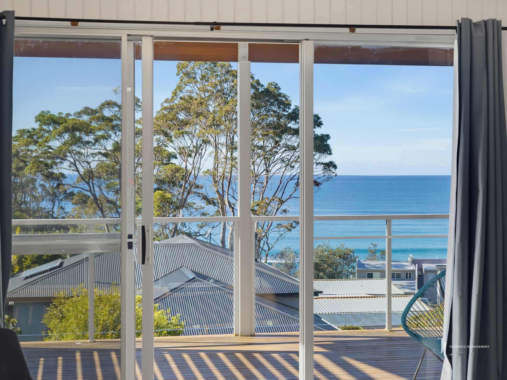 A balcony with a view of the sea and trees.