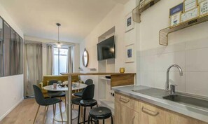 A compact kitchen with a dining area, a TV mounted on the wall, and a modern pendant light. - Beautiful appartement - 2CH/6P - Oberkampf (Paris)