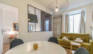 A modern living room with a round table, a sofa, and a large mirror. - Beautiful appartement - 2CH/6P - Oberkampf (Paris)