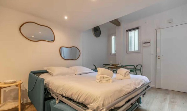 A bedroom with a bed, bedside tables, a mirror, a clock, and a door. - Beautiful apartment- 1BR/4P - Oberkampf (Paris)