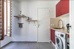 Eine kleine Küche mit Waschmaschine, Spüle und Holzböden.