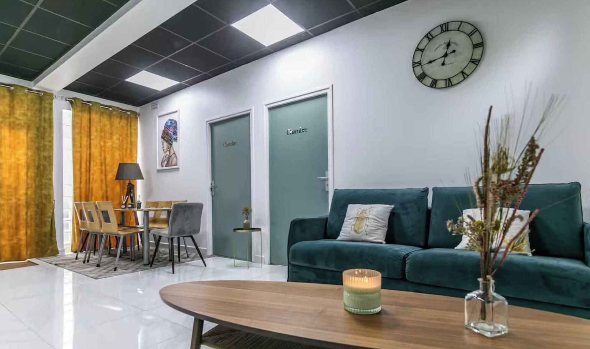 Ein moderner Empfangsbereich mit einem Holzbüro, einem grünen Sofa, einer Uhr und einer Tür mit der Aufschrift 'Camizze'.