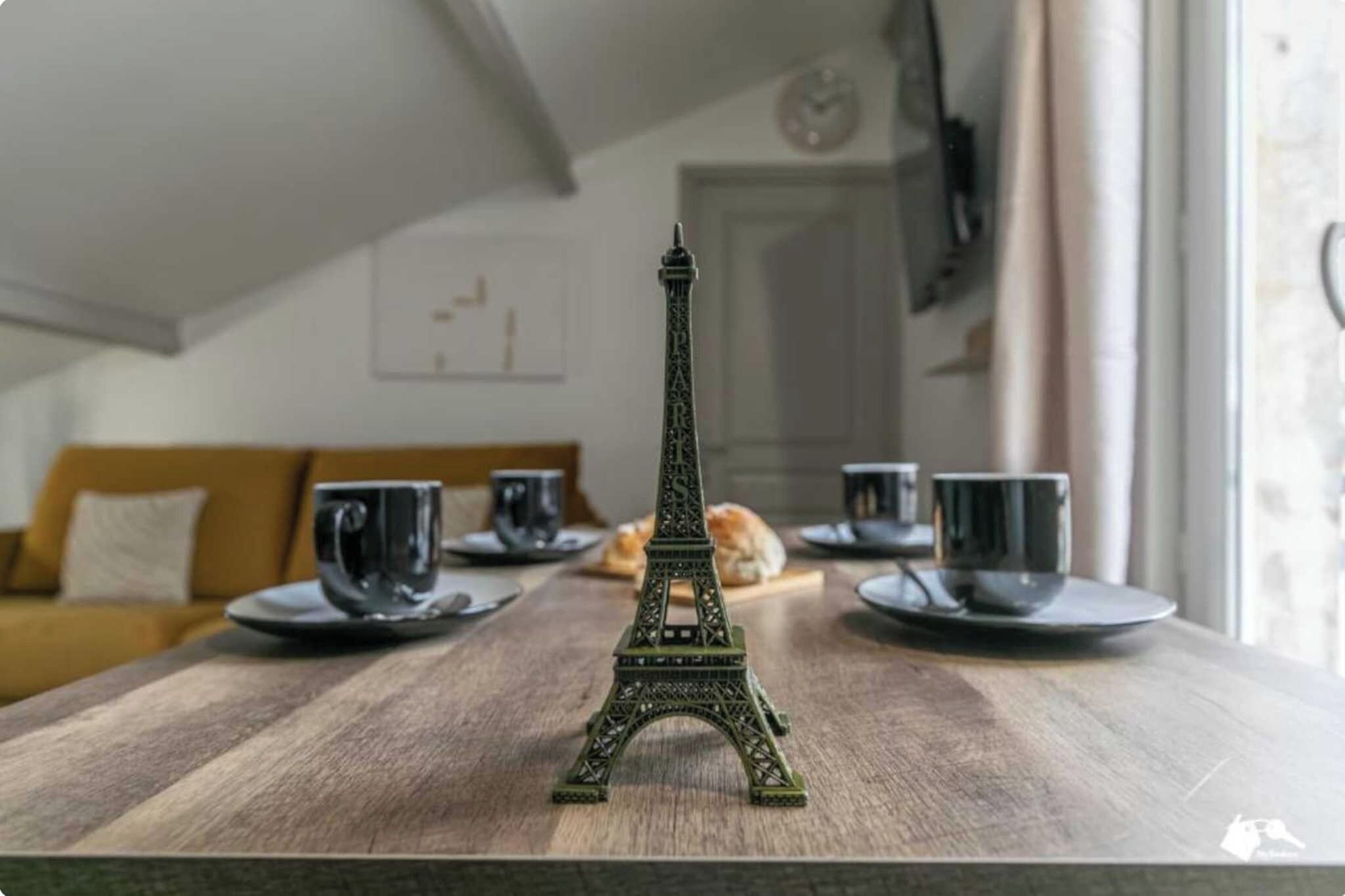 A model of the Eiffel Tower on a wooden table with plates and cups.