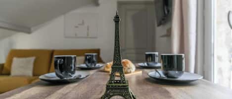 A model of the Eiffel Tower on a wooden table with plates and cups.
