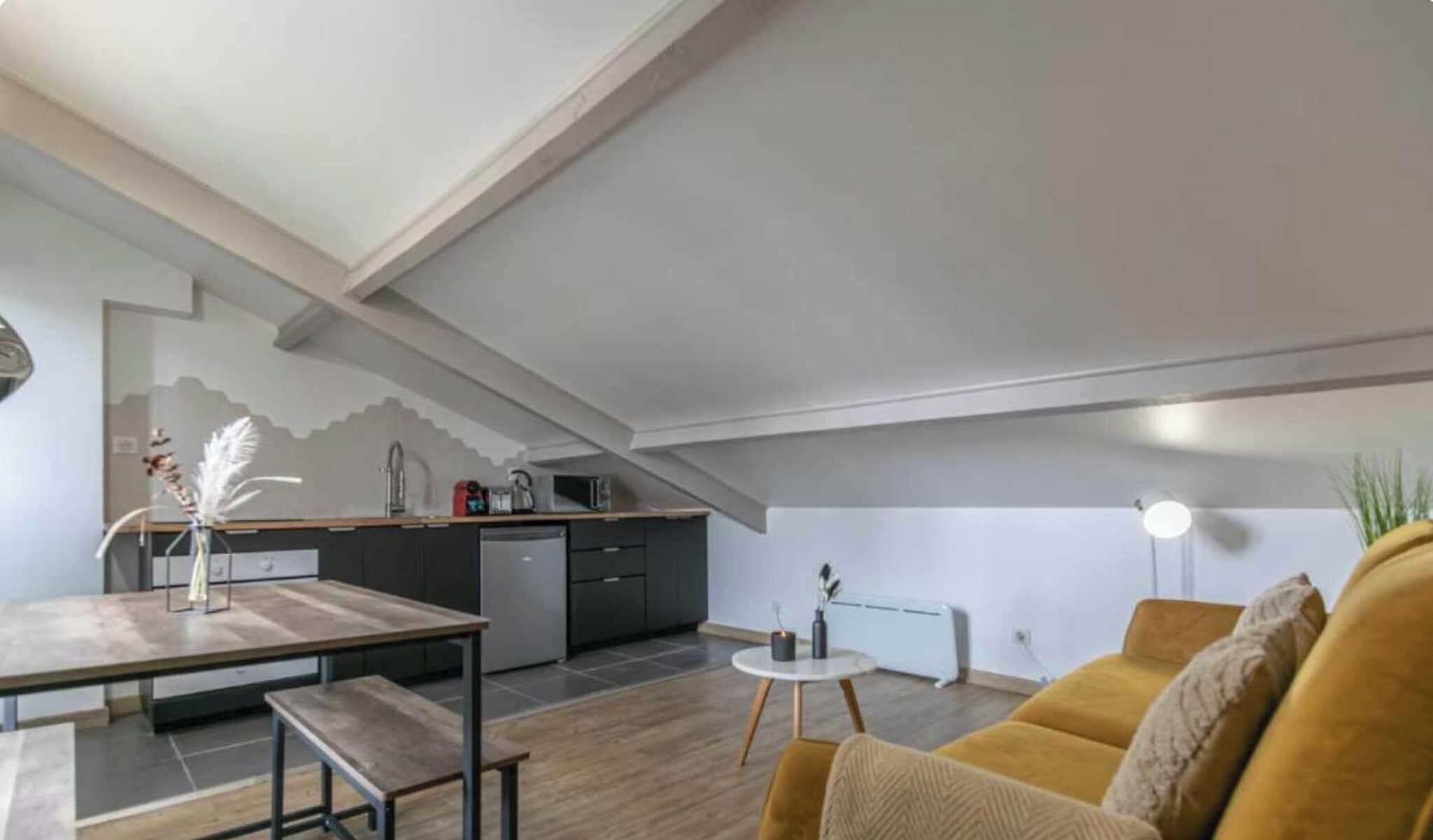 A modern loft-style living space with a kitchen, dining area, and seating area.