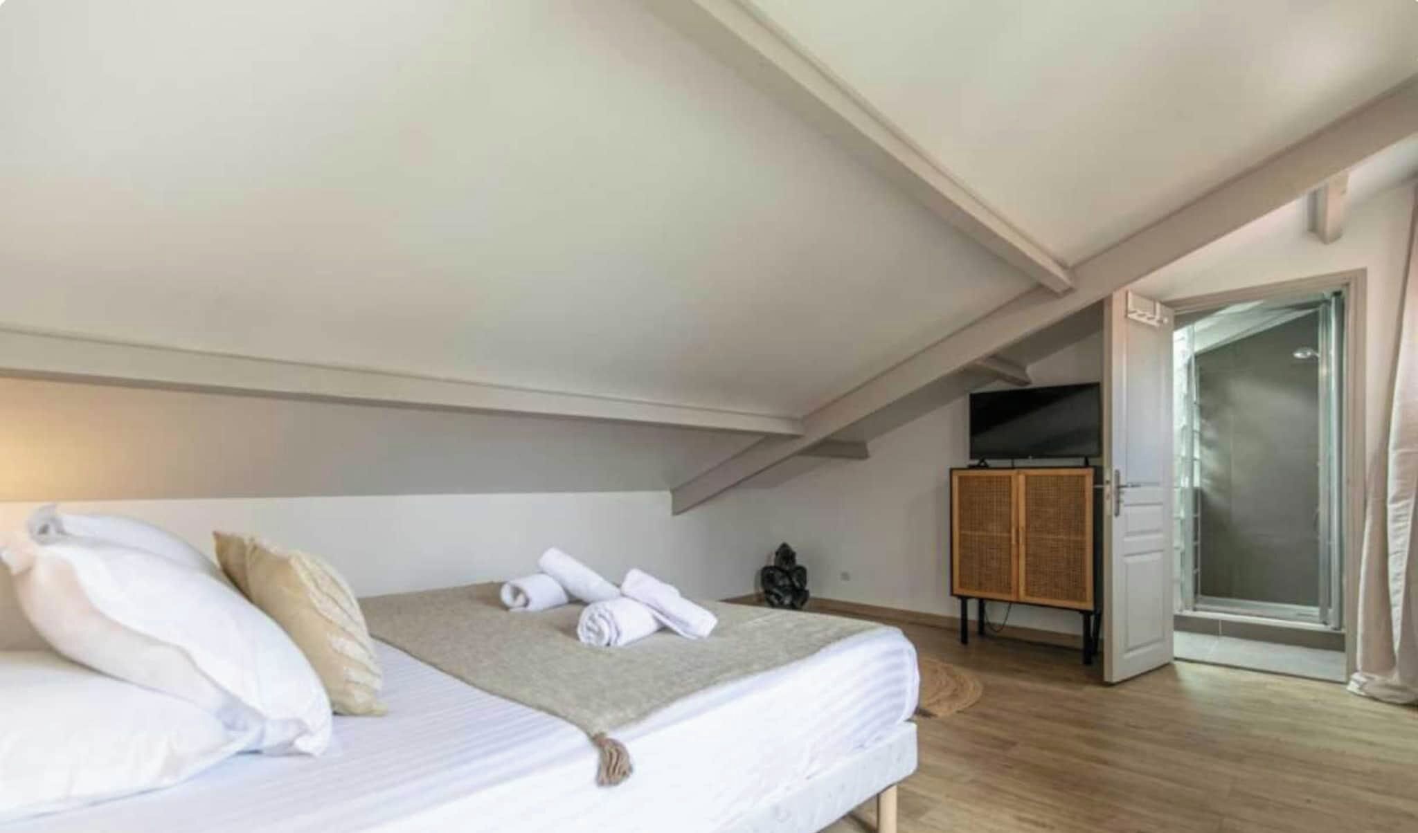 Een slaapkamer met een bed, een televisie en een deur naar een badkamer.