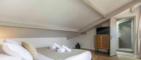 A bedroom with a bed, a television, and a door leading to a bathroom.