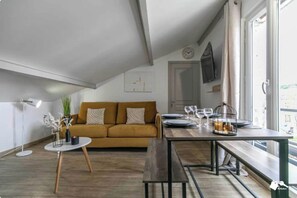 A modern living room with a sofa, a dining table, and a window with curtains. - Charming apartment  - 1CH/4P - Montreuil (Montreuil)