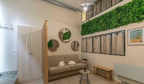 Ein modernes Interieur mit einer Couch, einem runden Spiegel, einer Bank und einer wandhängenden Zimmerpflanze.