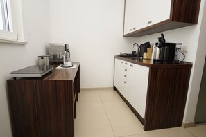 Een kleine keuken met een inbouwfornuis, een koffiezetapparaat en een magnetron.