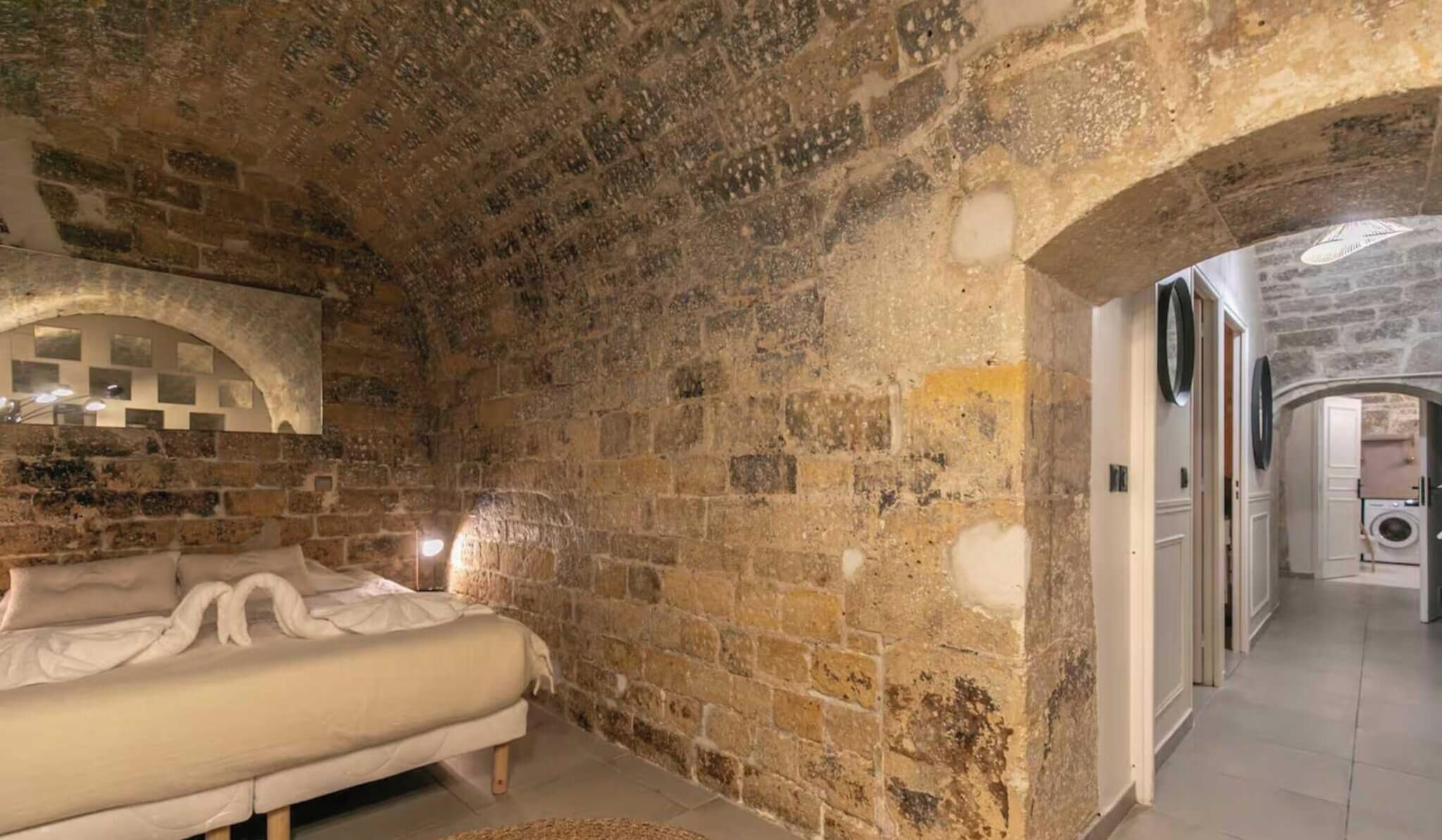 Ein Zimmer mit Steinwand, einem Bett und einem Flur zum Badezimmer.