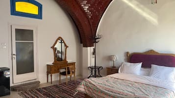 Un dormitorio con cama, cómoda, espejo, lámpara y puerta.