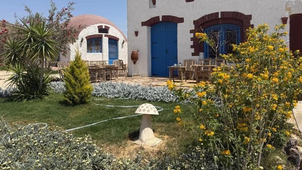 Un edificio con fachada blanca, puertas azules y una estructura en forma de cúpula.